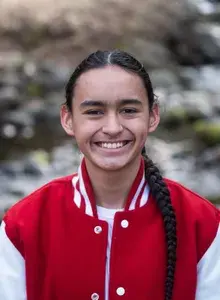 Braedon smiling wearing a red bomber jacket