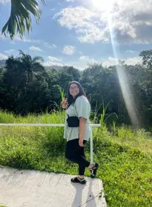 Jessica smiling outdoors with a peace sign up