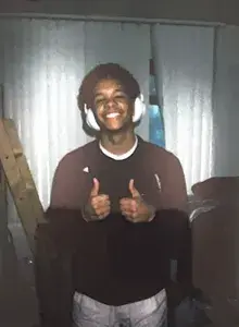 Jason smiling with white headphones on, holding up two thumbs up