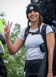 Fatima smiling with a backpack on, holding up a peace sign